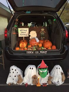 the back end of a vehicle with decorations in the trunk and pumpkins on the ground