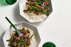 two white bowls filled with rice and meat on top of a table next to green drinks