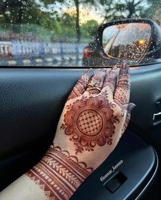 a woman's hand on the dashboard of a car with her arm and wrist covered in hendi