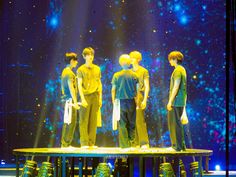 four young men standing on top of a table