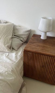 a bed with white sheets and pillows next to a night stand on top of it