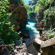 stairs lead down to a river with blue water in the middle and green trees on either side