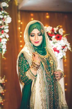 a woman dressed in green and gold is posing for the camera with her hands clasped