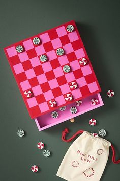 a pink and red checkerboard board next to candy canes on a green surface