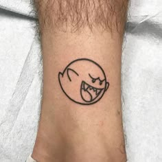 a black and white tattoo on the ankle of a man's foot with an angry face