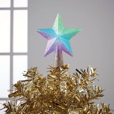 a christmas tree with a star decoration on it's top and gold tinsel