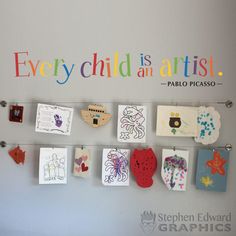 there are many pictures on the wall and some magnets in front of them that say every child is an artist