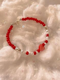 a red beaded bracelet with a heart charm on top of white furnishing