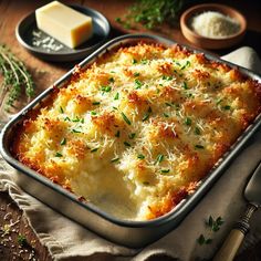 a casserole dish with parmesan cheese and herbs on the table next to it