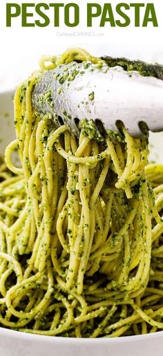 a white bowl filled with green pesto pasta and a spatula on top of it