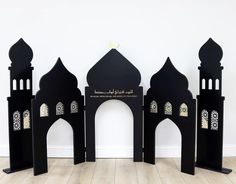 three black and gold arches with arabic writing on them in front of a white wall