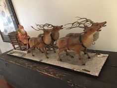 three figurines of reindeer pulling a sleigh on top of a table