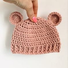 a hand is touching the top of a crocheted hat that has ears on it