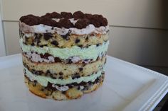 a layered cake on a white plate with chocolate chips and cream filling, is ready to be eaten