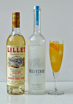 two bottles of alcohol next to a glass filled with orange juice and an empty bottle