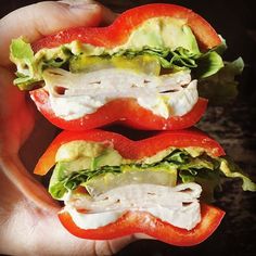 two halves of a sandwich in someone's hand with tomatoes and lettuce