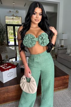 a woman in green pants and crop top posing for the camera with her hand on her hip