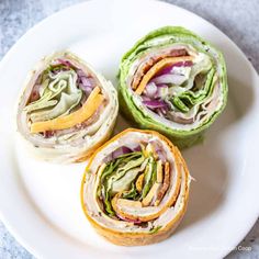 three sandwiches on a white plate with lettuce and cheese