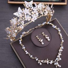 a tiara with pearls and butterflies on it next to a necklace and earring