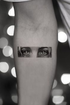 a woman's leg with an eye tattoo on the left side of her arm