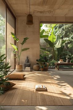 an open room with plants and books on the floor, in front of large windows