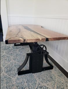 a wooden table sitting on top of a carpeted floor next to a white wall