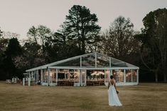 a bride standing in front of a glass house at sunset with her back to the camera