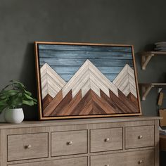 a painting is on top of a dresser next to a potted plant and bookshelf