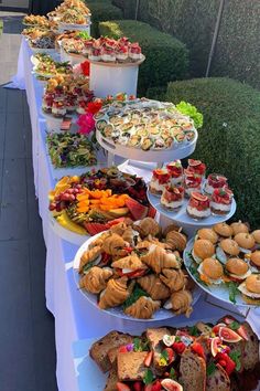 a long table topped with lots of sandwiches and pastries on top of white plates