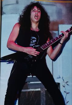 a man with long hair playing an electric guitar