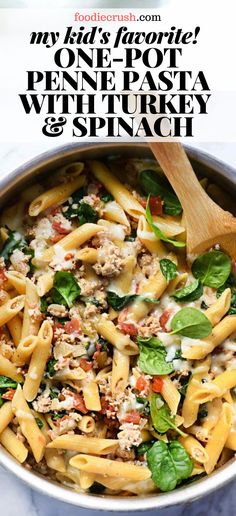 a pot filled with pasta and spinach on top of a table