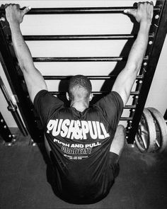 a man is doing squats in front of a barbell rack with one hand on his head