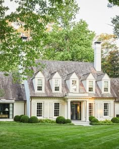 a large white house in the middle of a lush green yard with lots of trees