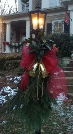 a christmas wreath on top of a pole in front of a house with stairs and lights