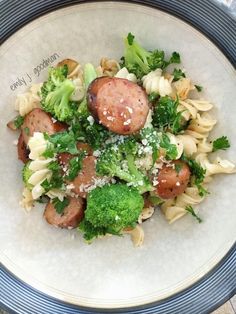 a white bowl filled with pasta and meat covered in broccoli on top of a table