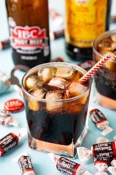 two glasses filled with ice and soda on top of a table