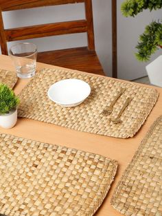 a table with place mats and plates on it, next to a plant in a vase