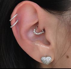 a woman wearing three different types of ear piercings