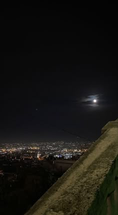 the moon is shining brightly in the night sky over a cityscape and hills