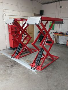 two red scissor lifts in a garage