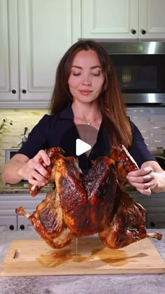 a woman cutting up a whole turkey on a wooden board