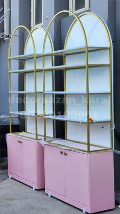 two pink and gold bookcases sitting next to each other