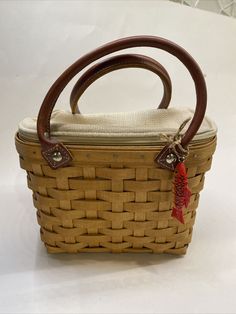 a woven basket with handle and handles on the top is sitting on a white surface