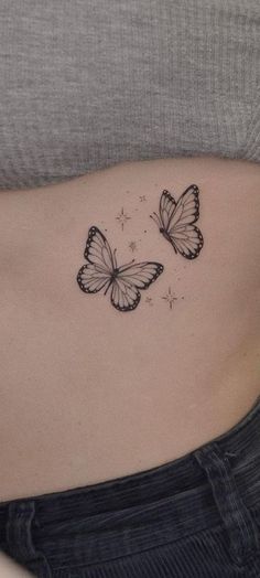 a woman's stomach with two butterflies tattoo on the side of her belly,