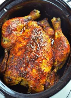 a close up of a cooked chicken in a crock pot on top of a stove