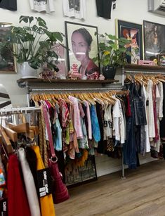 a clothing store with clothes hanging on racks and pictures above the rack in front of it