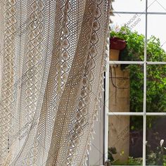 an open window with a lace curtain in the foreground and a potted plant behind it