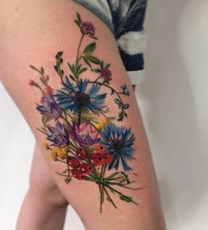 a close up of a person's thigh with flowers tattooed on the leg and behind her