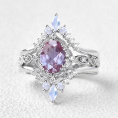 a ring with an oval shaped purple stone surrounded by smaller white and light blue stones