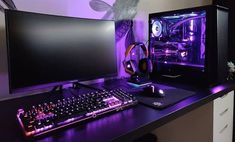 a desk with a keyboard, mouse and monitor on it in front of a purple light